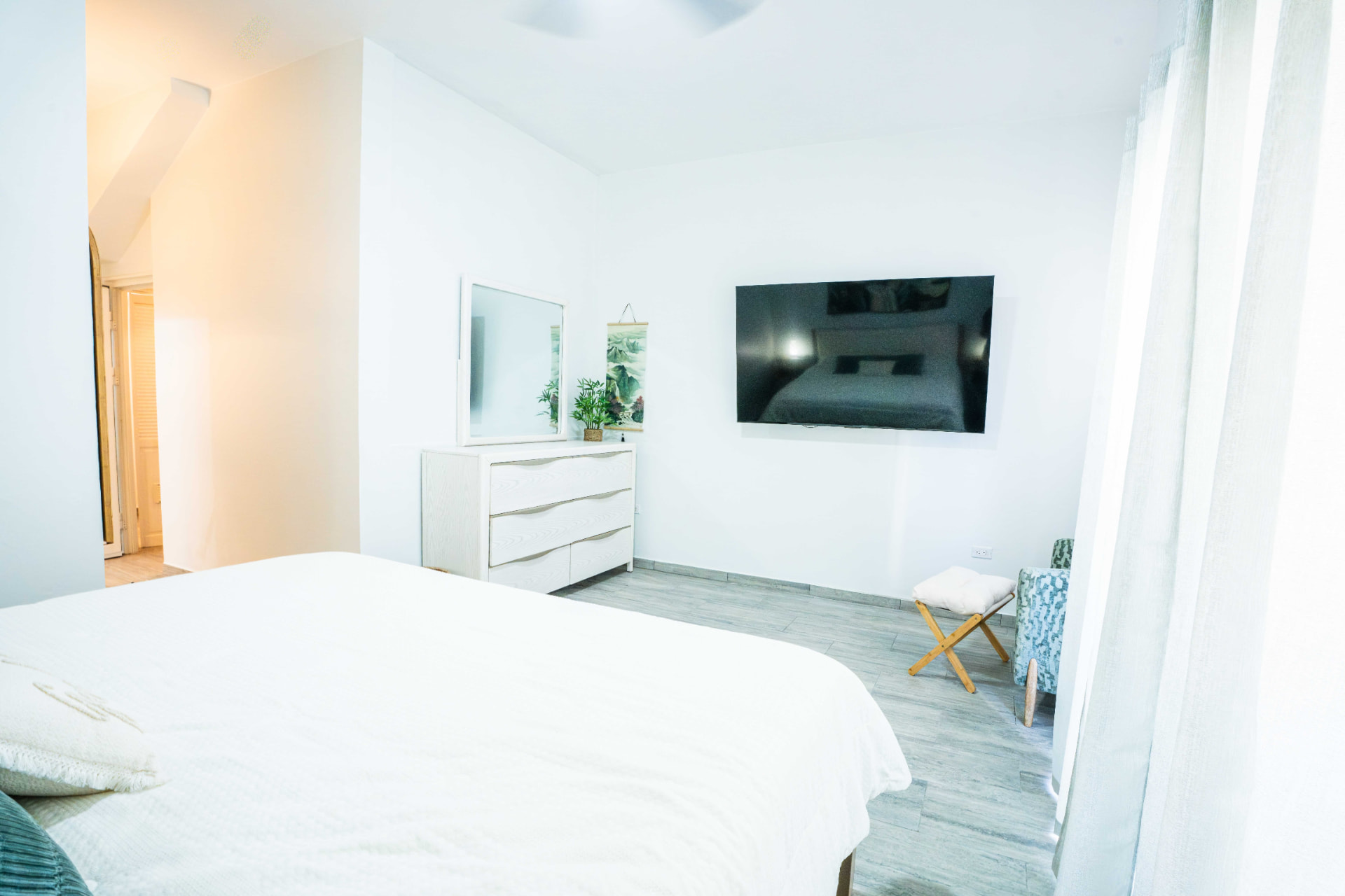 Bright bedroom with white linens and wall mounted television